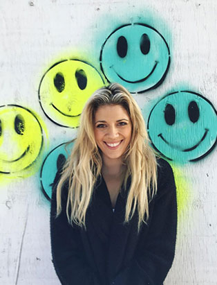 jessica clark in front of smiley face graffiti