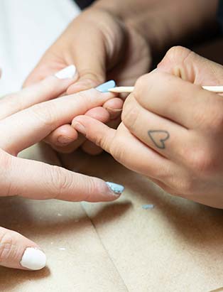 nail student uses an orange stick to remove soaked gel nails