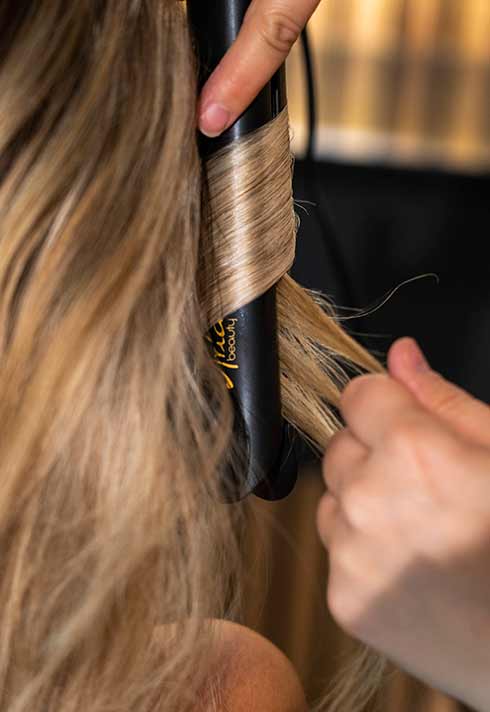 stylist and BMC pro hair graduate Lara Dillman curling hair at BRUSH Salon