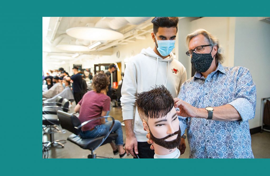 student with instructor hands on barbering school