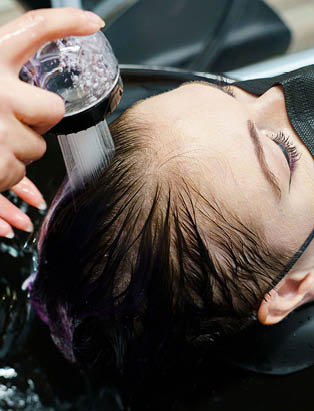 model with purple hair getting shampooed at the salon sink