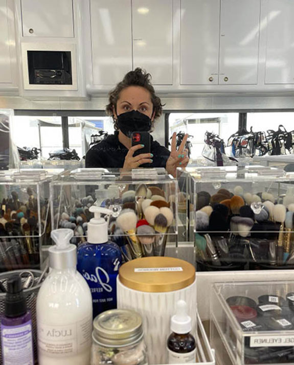 Film & TV Makeup Artist Sarah Buckley on set, clear buckets of makeup brushes in foreground