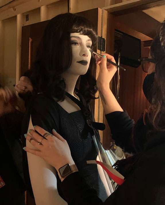 Film & TV Makeup Artist Sarah Buckley uses a brush to apply gothic makeup on a dark haired actress