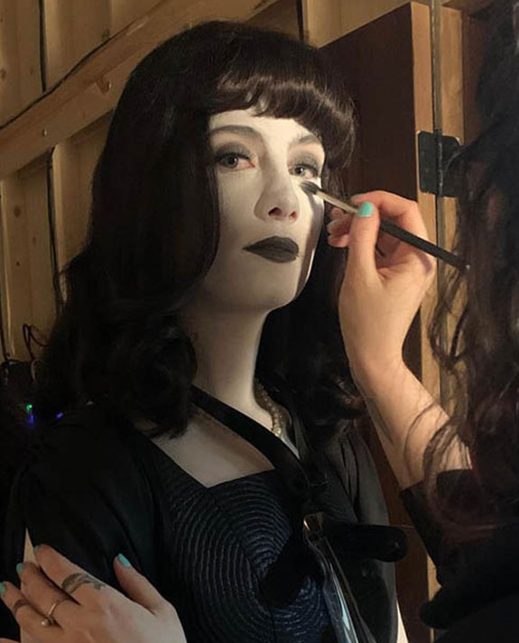 Film & TV Makeup Artist Sarah Buckley uses a brush to apply gothic makeup on a dark haired actress