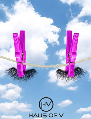 Two false lashes hang on a laundry line held up by purple clips, blue sky in background