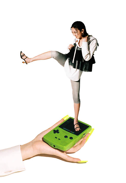 Alex Yu model stands on a gameboy device kicking into the air