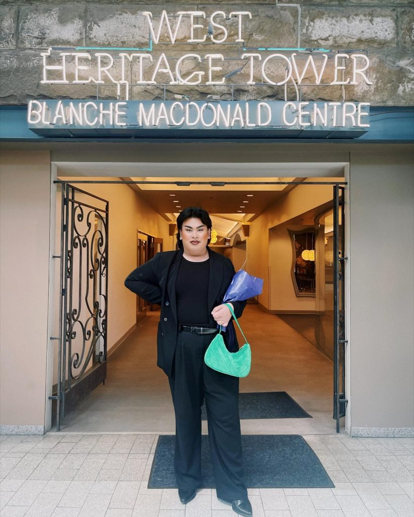 Robby De Mesa, Blanche Macdonald Gradaute stands in front of the Blanche Macdonald Sign at our City Square Campus