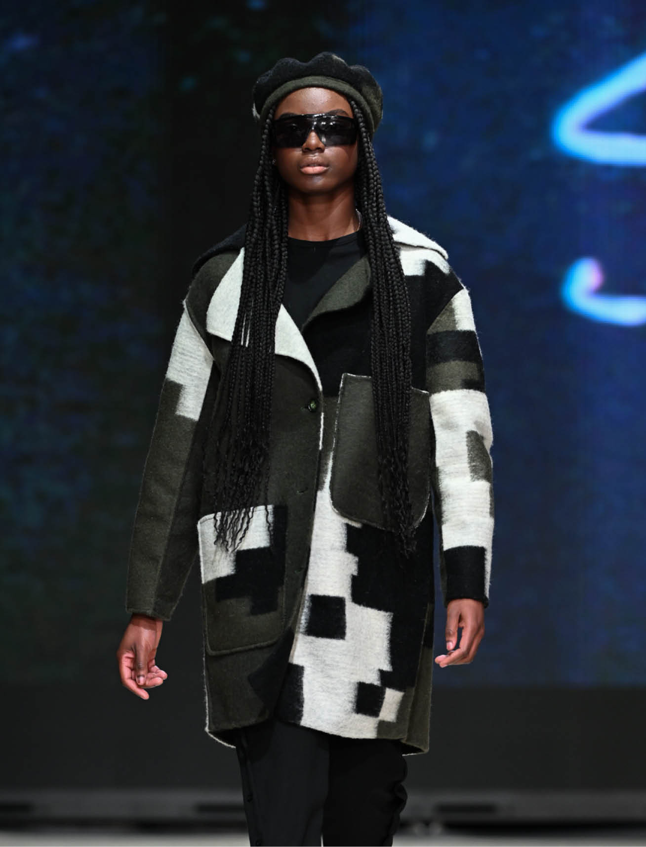 model wears grey, white, black, patchwork coat by blanche macdonald graduate sujitha shivajothi