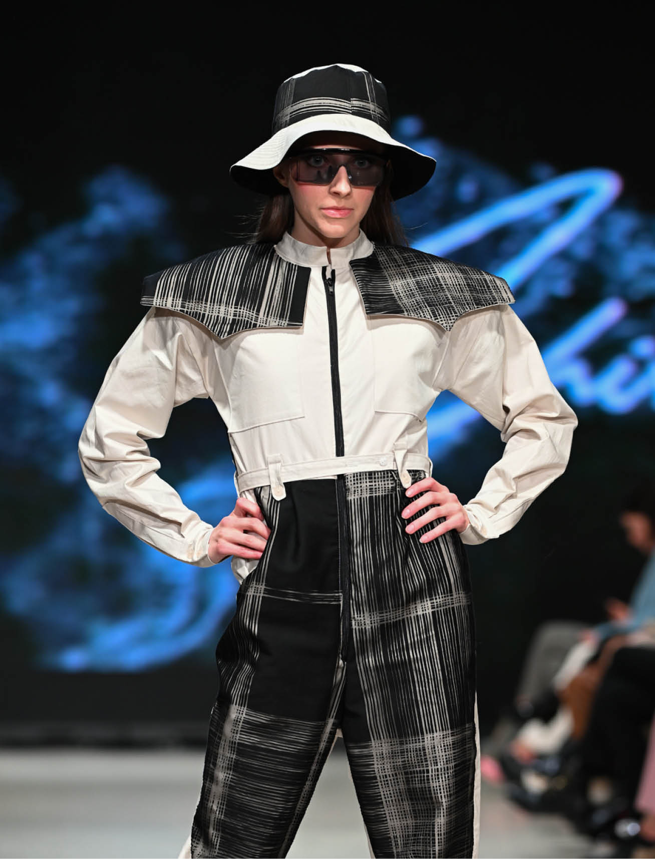 model in plaid cape, dark pants, and white long sleeve top designed by fashion designer sujitha shivajothi