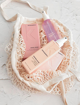 4 Kevin Murphy pink products in a mesh beach bag on a marble background