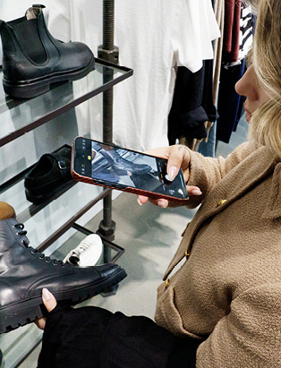 Kimberly Schmalz taking a photo of black boots in a retail store