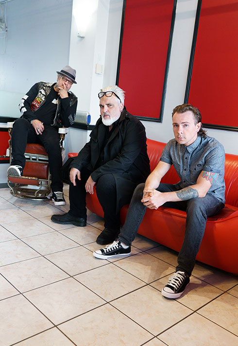 Ash sitting with his friend on a red couch 