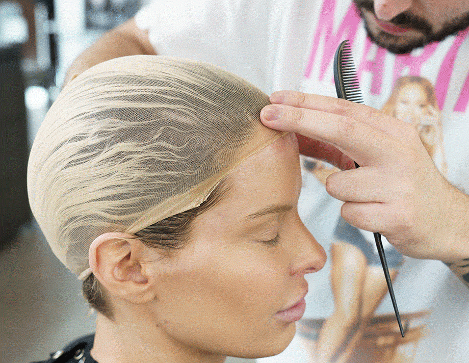 Dylan putting a long blonde wig on a female model 