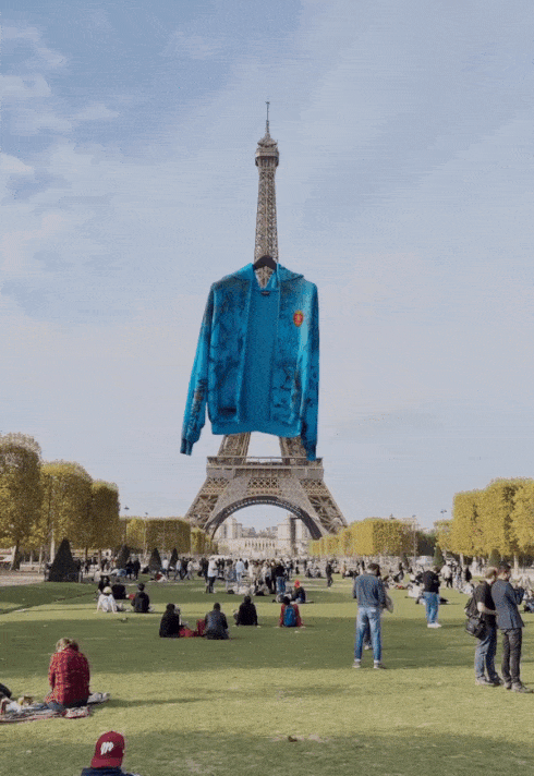 a blue jacket is floating in front of Eiffel Tower under a blue sky