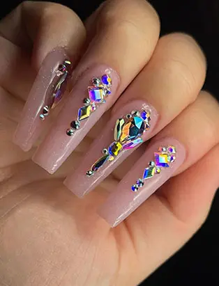close0up shot of a nude coffins long nail design with jewelry designs