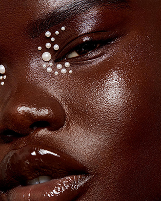 Close up of a Black model with white pearls gemstones near her eyes; makeup designed by Bridal Hair and Makeup Artist Tanin Nicole