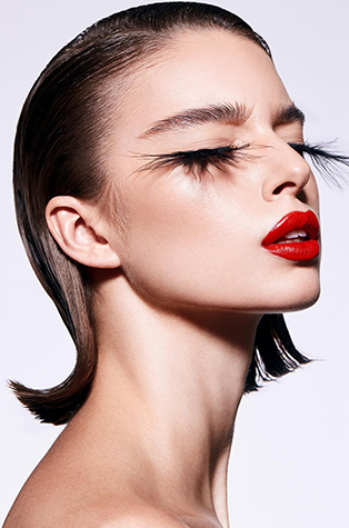 A short hair model wearing long eyelash extensions and a red lip.